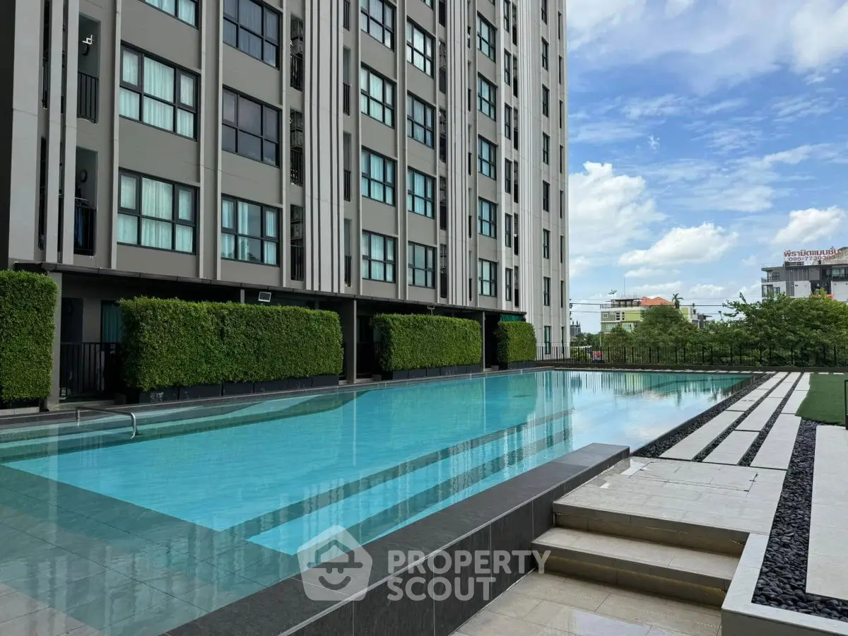 Modern apartment building with luxurious outdoor pool and lush greenery.