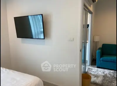 Modern bedroom with wall-mounted TV and cozy adjacent living area.