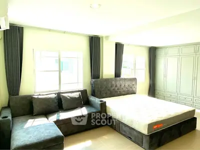 Spacious bedroom with large bed and cozy sofa, ample natural light and built-in wardrobe.