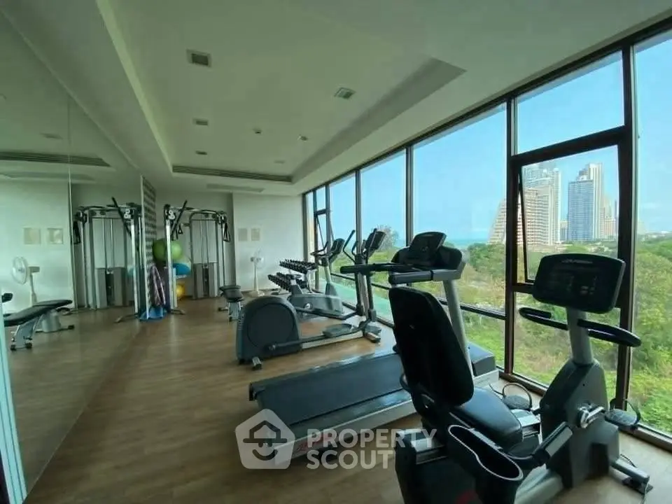 Modern gym with city view, featuring state-of-the-art exercise equipment and floor-to-ceiling windows.