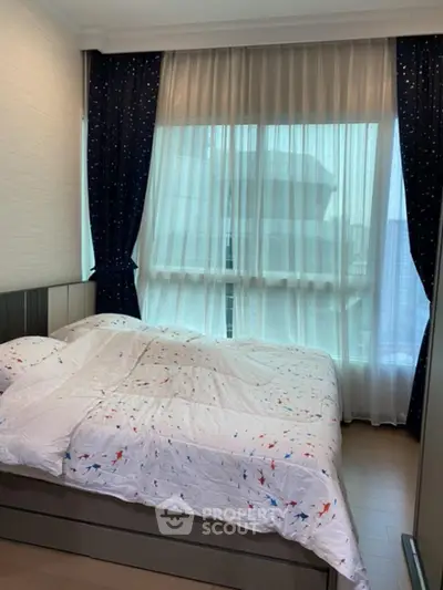 Cozy bedroom with large window and stylish curtains, perfect for relaxation.