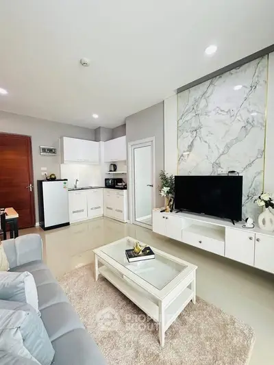 Modern living room with sleek kitchen, marble accent wall, and cozy seating area.