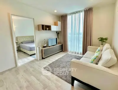 Modern living room with cozy sofa and large window, adjacent to a stylish bedroom.