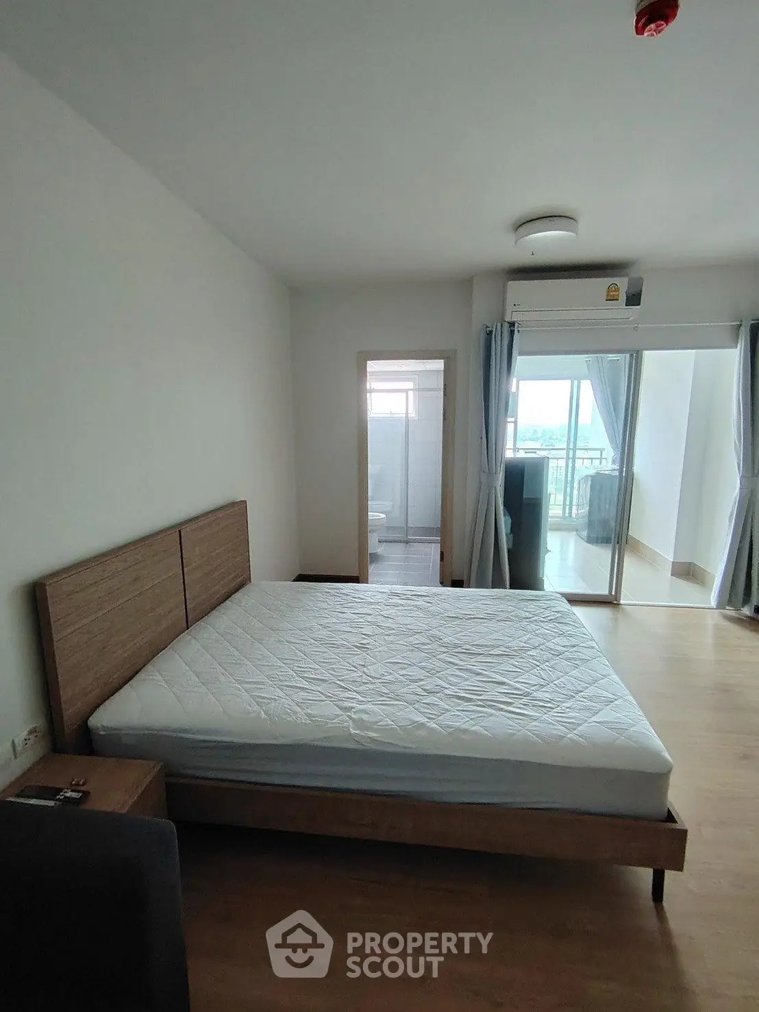 Spacious bedroom with balcony access and modern furnishings in a bright apartment.