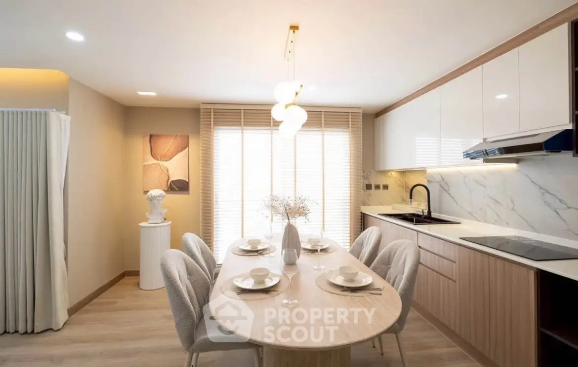 Elegant dining area with modern kitchen, featuring sleek cabinetry and stylish lighting.