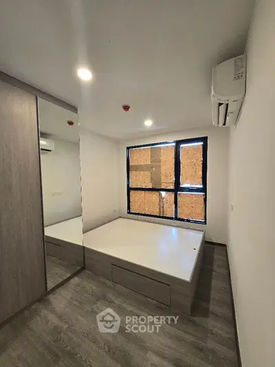 Modern bedroom with built-in wardrobe and large window in a stylish apartment.