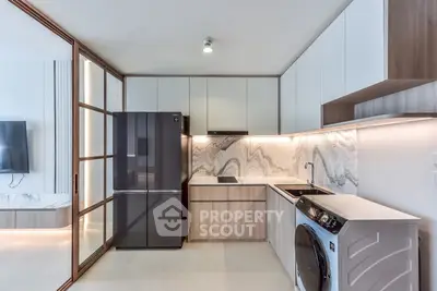 Modern kitchen with sleek appliances and marble backsplash in a stylish apartment.