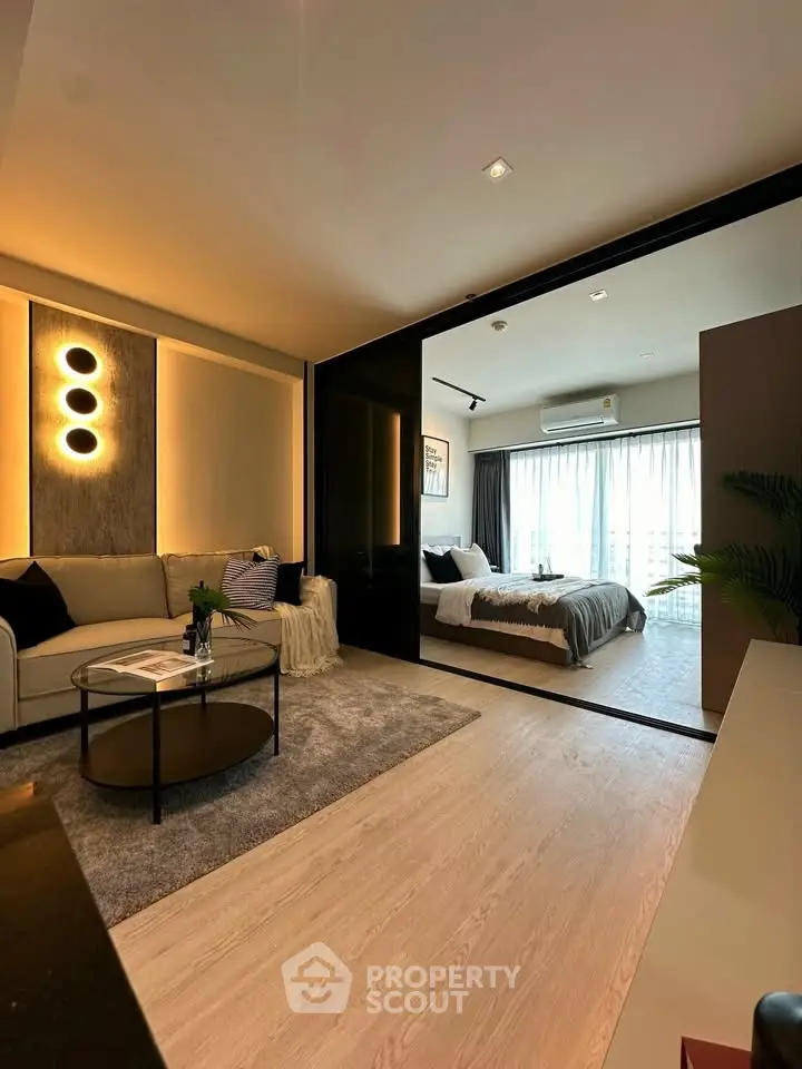 Modern open-plan living room with cozy bedroom, stylish lighting, and large windows for natural light.