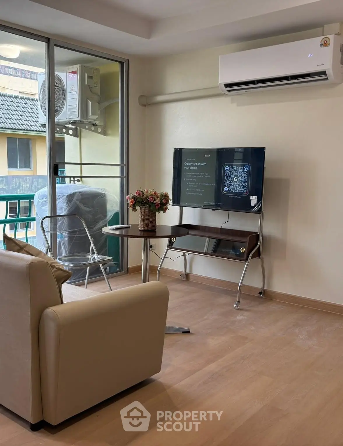 Modern living room with air conditioning and balcony view, featuring a sleek TV setup and comfortable seating.
