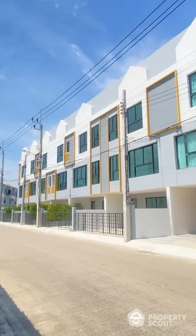 Modern townhouse exterior with sleek design and large windows on a sunny day.