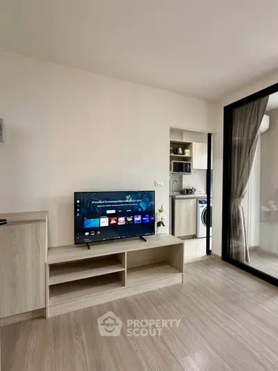 Modern living room with sleek TV stand and open kitchen layout in stylish apartment.