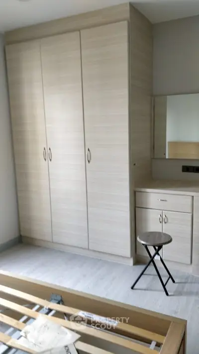 Modern bedroom with built-in wardrobe and vanity, featuring sleek design and neutral tones.