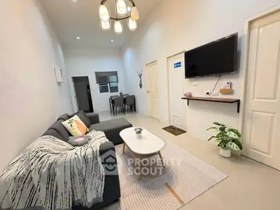 Modern living room with cozy sofa, wall-mounted TV, and stylish decor in a bright apartment.