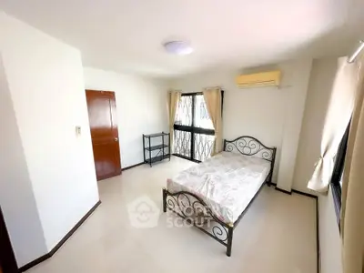 Spacious bedroom with elegant metal bed frame and large windows for natural light.