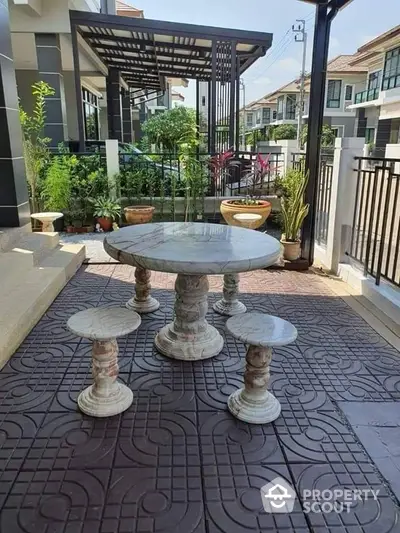 Charming outdoor patio with elegant stone table and lush greenery in modern residential area.