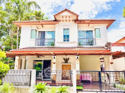 Charming two-story house with a tiled roof, lush greenery, and a welcoming entrance in a serene neighborhood.