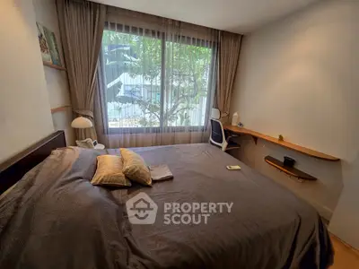 Cozy bedroom with large window and modern decor, perfect for relaxation.