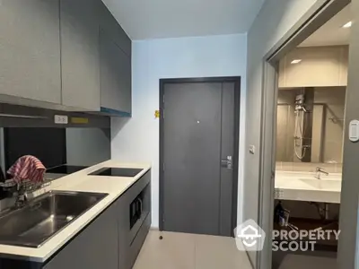 Modern compact kitchen with sleek cabinetry and adjacent bathroom featuring a stylish bathtub.