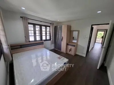 Spacious bedroom with modern furniture and large windows offering natural light.