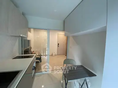 Modern kitchen with sleek cabinetry and open layout leading to living area.