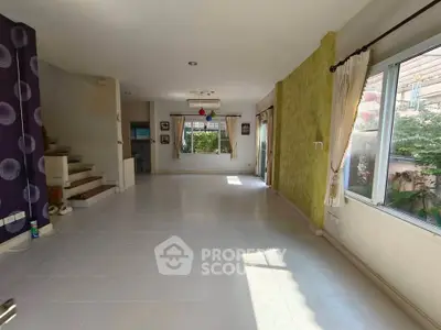Spacious living room with large windows and staircase, perfect for family gatherings.