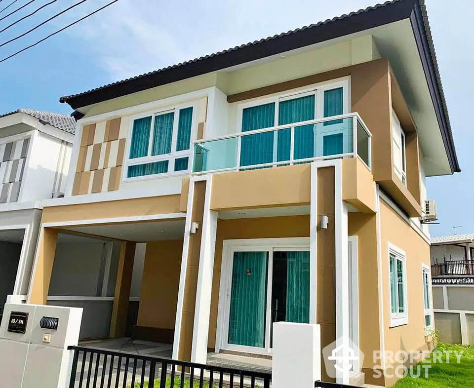 Modern two-story house with large windows and balcony in a suburban neighborhood.