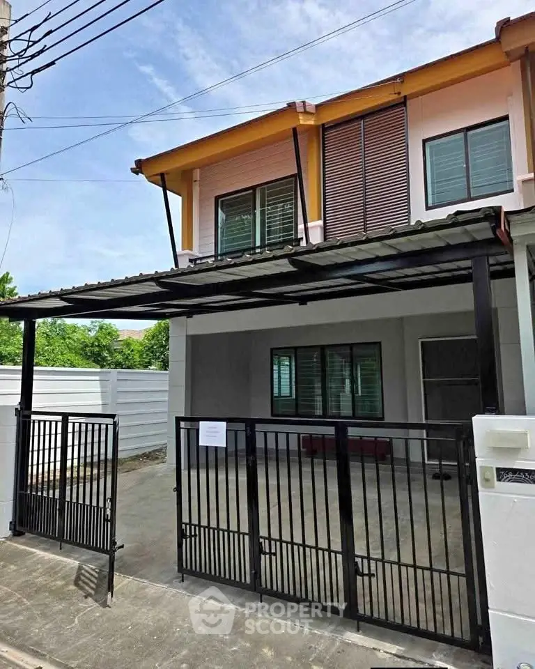 Modern two-story house with gated driveway and sleek exterior design.