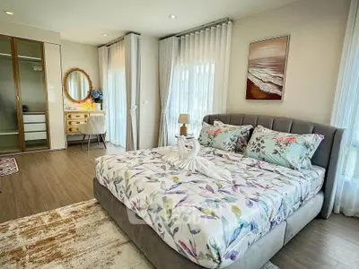 Luxurious bedroom with elegant decor and natural light, featuring a stylish bed and cozy workspace.