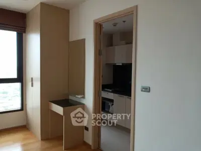 Modern apartment interior with wooden flooring and compact kitchen area.