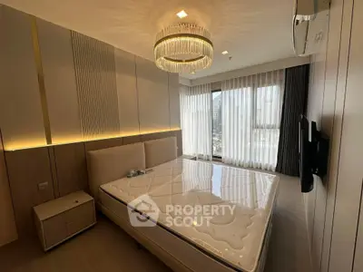 Luxurious bedroom with elegant chandelier and large windows offering stunning city views.