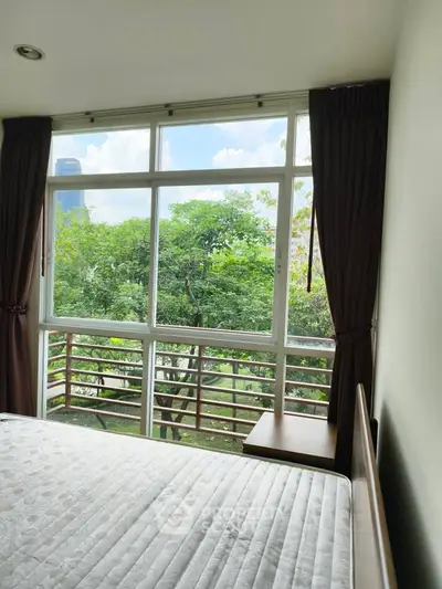 Bright bedroom with large window offering lush green view, perfect for nature lovers.