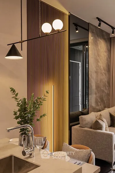 Modern living room with stylish decor and open kitchen layout, featuring elegant lighting and cozy seating.