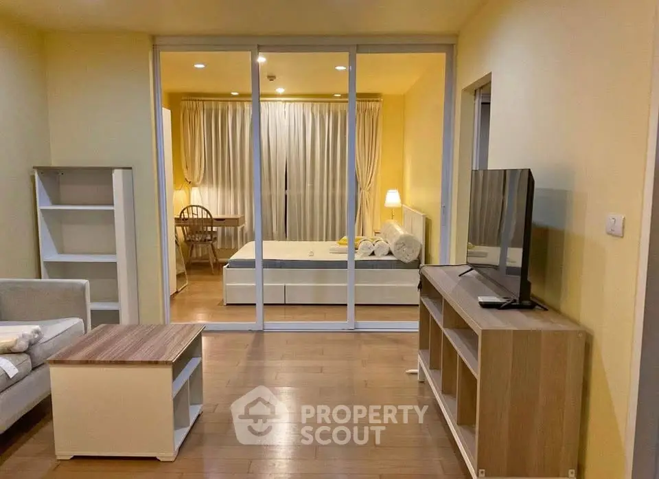 Spacious open-plan living room with modern furnishings and cozy bedroom view.