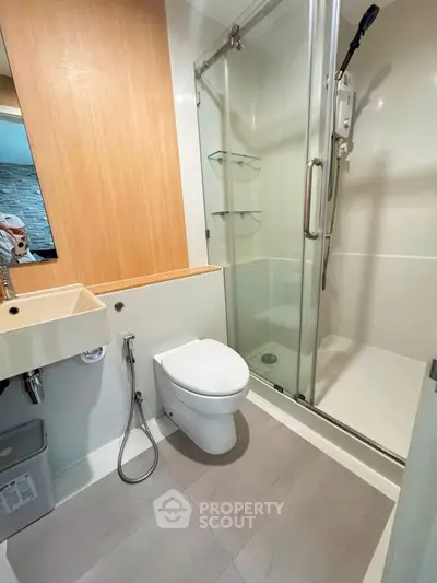 Modern bathroom with glass shower and sleek fixtures in contemporary apartment.