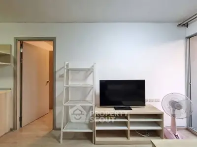 Modern living room with TV stand, shelving, and fan in a cozy apartment.