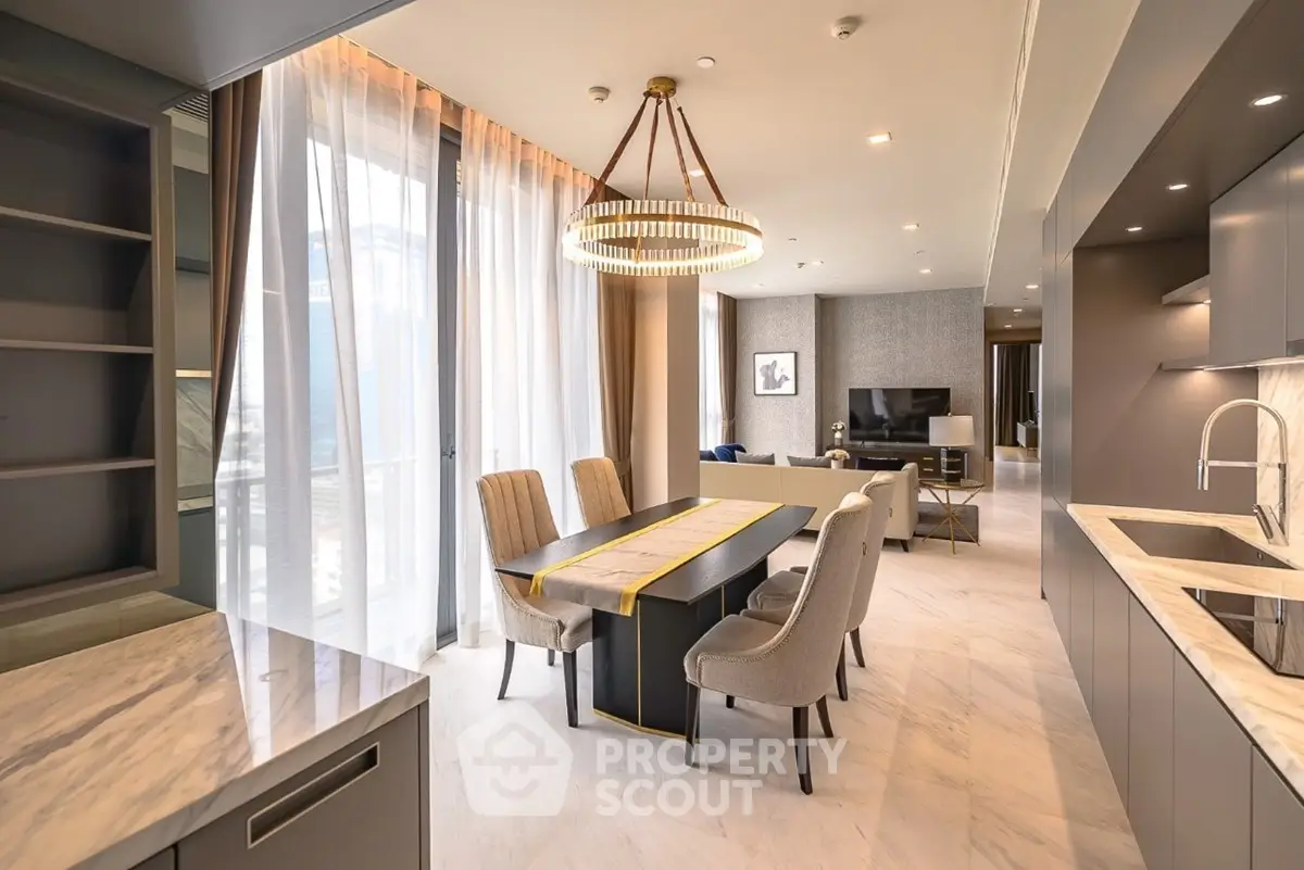 Luxurious modern dining area with elegant chandelier and open kitchen layout in high-end apartment.