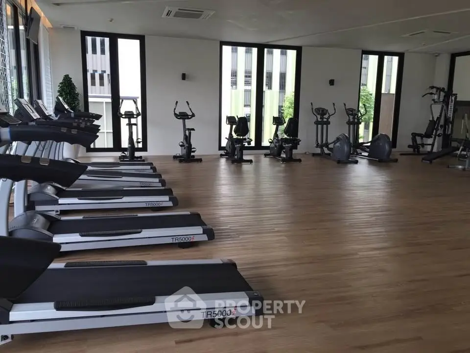 Spacious modern gym with state-of-the-art fitness equipment and large windows for natural light.