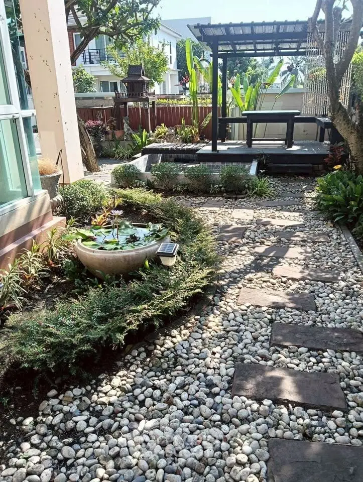 Charming garden with stone pathway and modern gazebo in a serene residential setting.