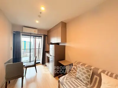 Modern living room with balcony view, stylish furniture, and compact kitchen area.