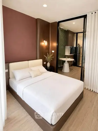 Modern bedroom with stylish decor and view into open kitchen area, perfect for urban living.