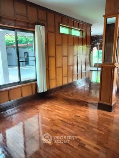 Spacious wooden interior with large windows and polished floors, perfect for elegant living.