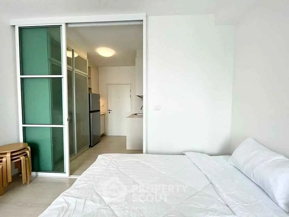 Modern studio apartment with sliding glass doors and compact kitchen