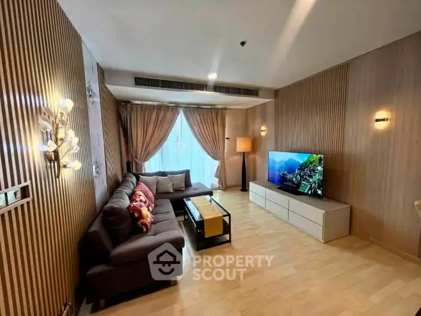 Modern living room with stylish decor and large TV, featuring elegant lighting and cozy seating area.