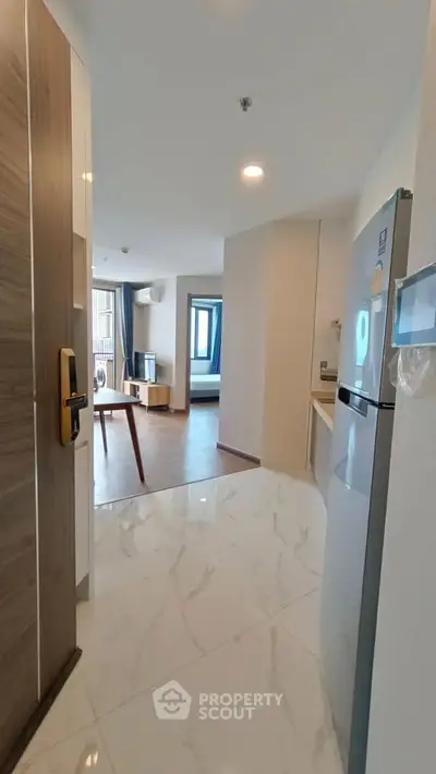 Modern apartment entrance with sleek kitchen and spacious living area, featuring elegant marble flooring.