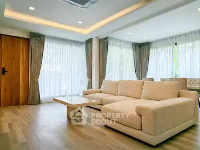 Spacious modern living room with elegant beige sofa and floor-to-ceiling windows.