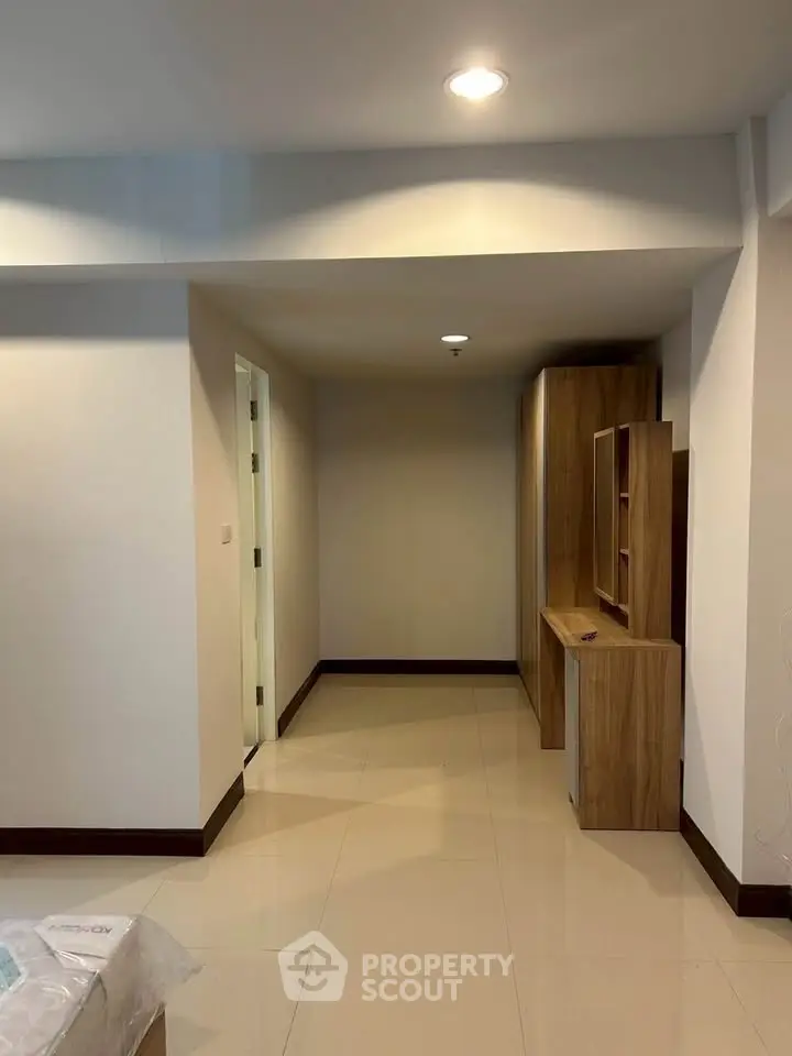 Spacious hallway with modern wooden cabinetry and recessed lighting in a contemporary apartment.