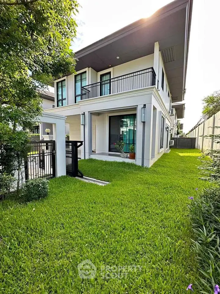 Modern two-story house with lush green lawn and sleek balcony design.