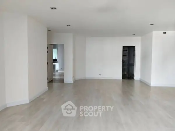 Spacious empty room with light wood flooring and neutral walls, ready for customization.