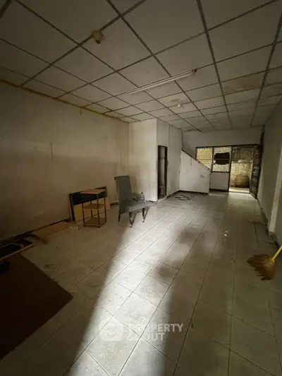 Spacious interior with tiled flooring and minimal furnishings, ideal for renovation or customization.