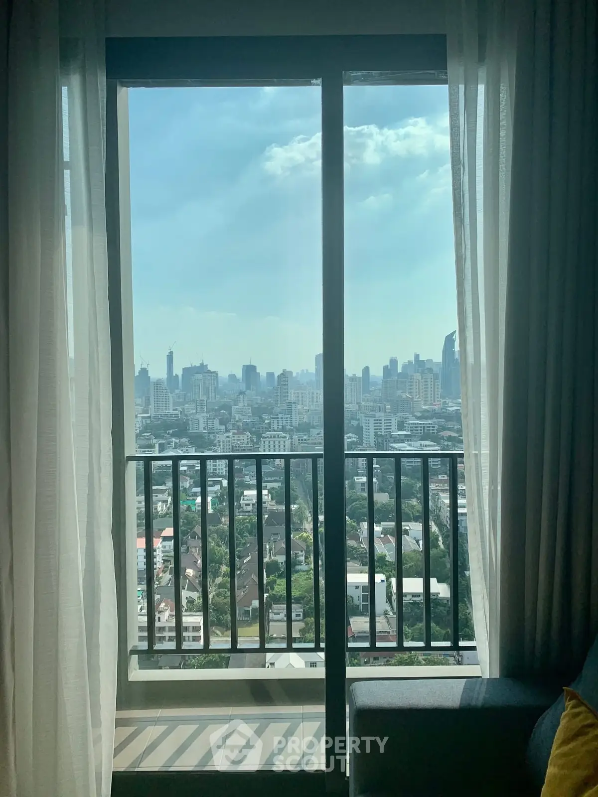 Stunning city view from a modern apartment balcony with floor-to-ceiling windows.